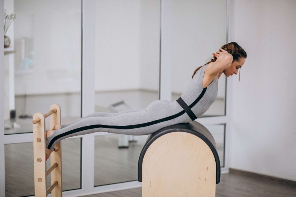 perempuan sedang melakukan perenggangan dengan menggunakan ladder barrel pilates