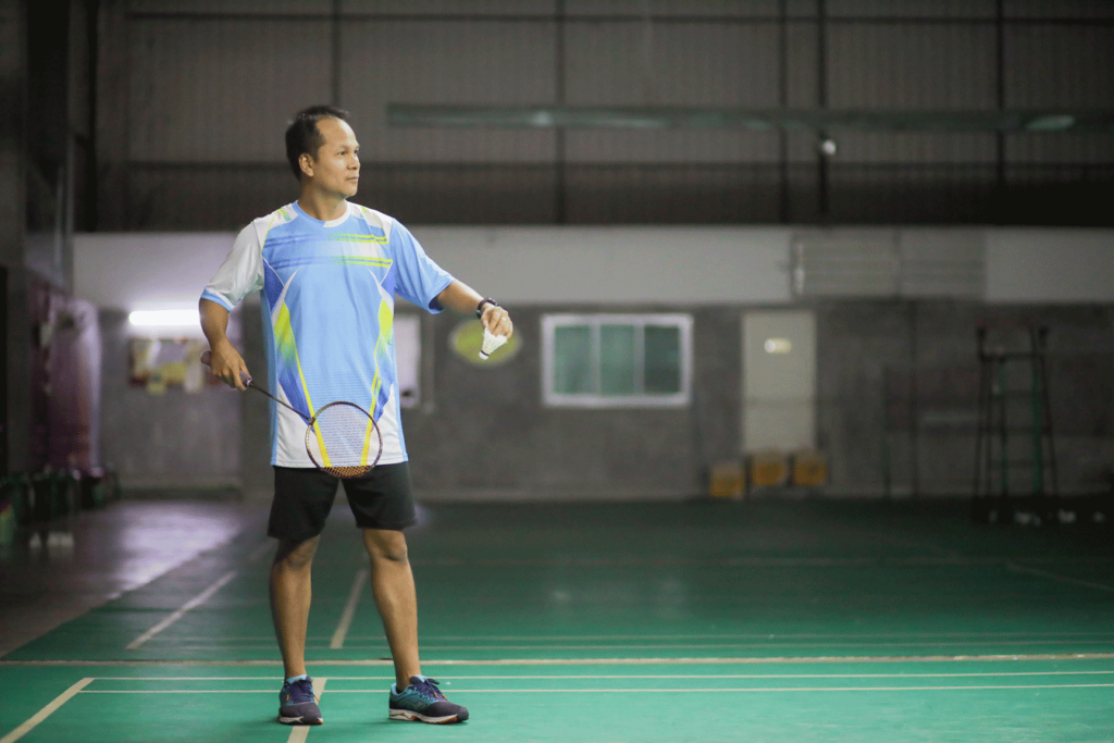 Seorang pelatih badminton di lapangan bulu tangkis sedang bersiap untuk servis